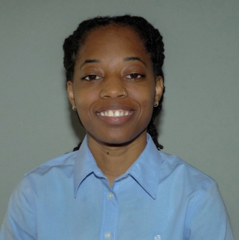 Person wearing a light blue collared shirt with dark braids, smiling, and posed against a plain background.